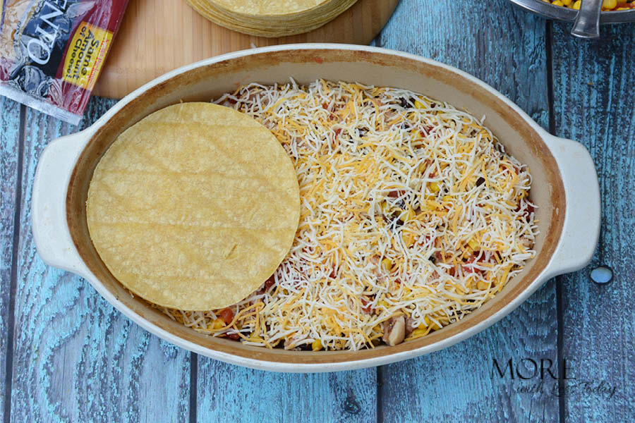 adding the cheese on and layering corn tortillas to make Four Cheese Bake recipe