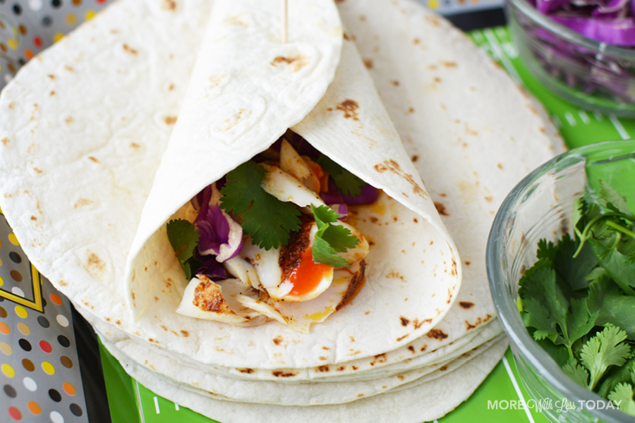 rolling fish taco ingredients into a flour tortilla