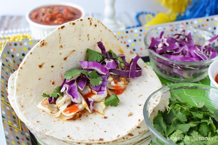 adding ingredients into a flour tortilla for fish tacos