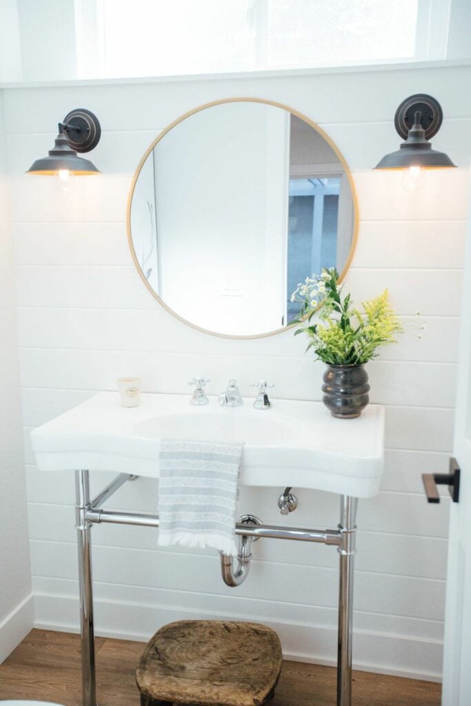 updating a guest bathroom with new light fixtures and a mirror over a sink