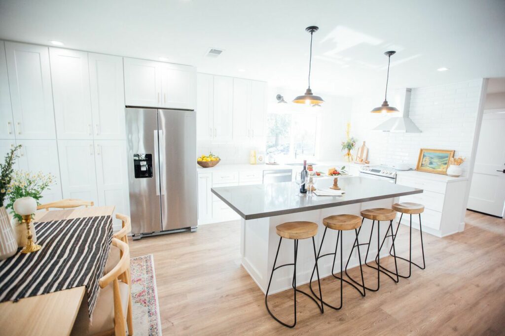 On Trend Lighting Fixtures for a California Condo Remodel featuring kitchen island with barstools and overhead lighting.