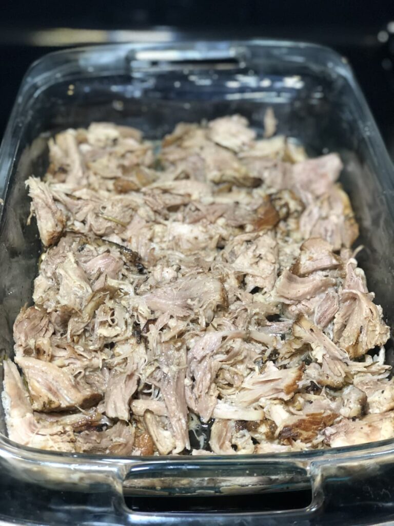 shredded pork carnitas meat in a glass pan