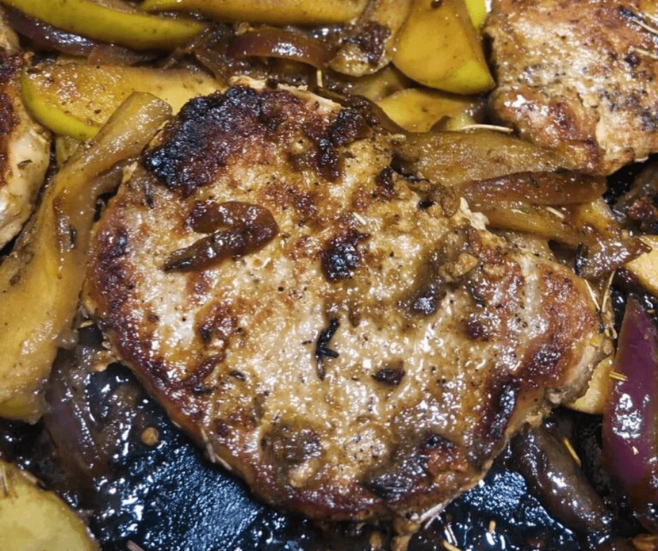 Cooked boneless pork chop around cooked apples and onions