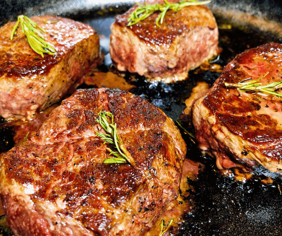 Freshly cooked Omaha Steaks Ribeye on a skillet with a sprig of Rosemary