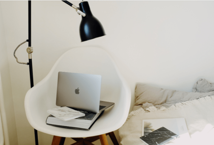  a standing black lamp illumiating a computer and a book for task lighting