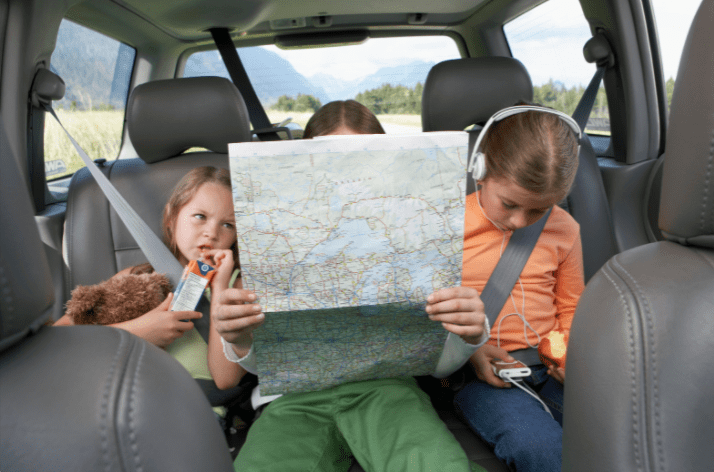 kids on a road trip looking at a map