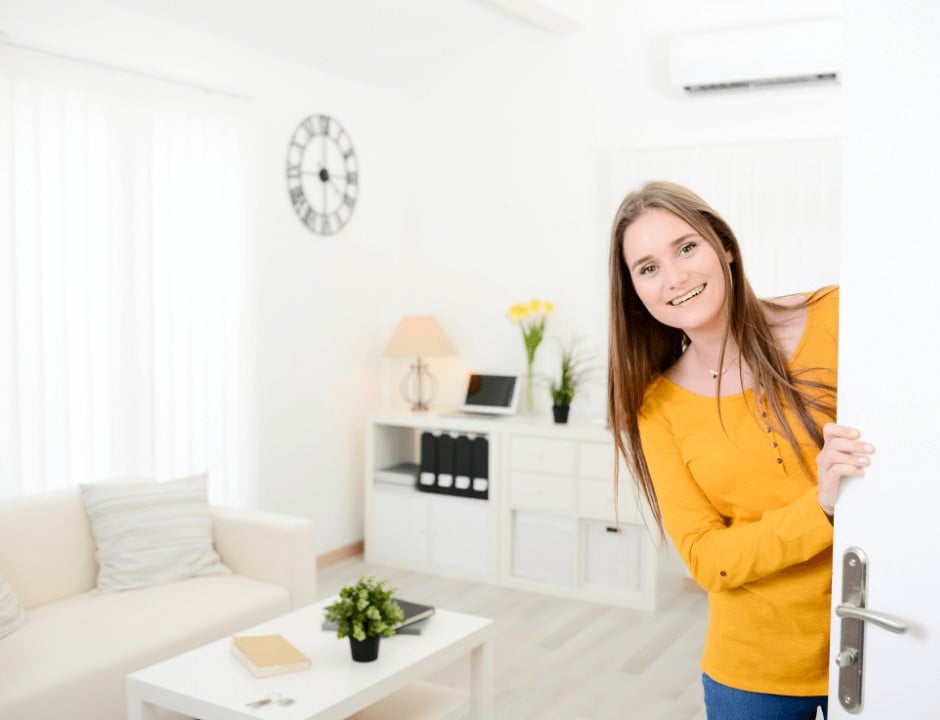 A woman opening a door for a guest - 10 Item Checklist to Prepare Your Home for Overnight Guests