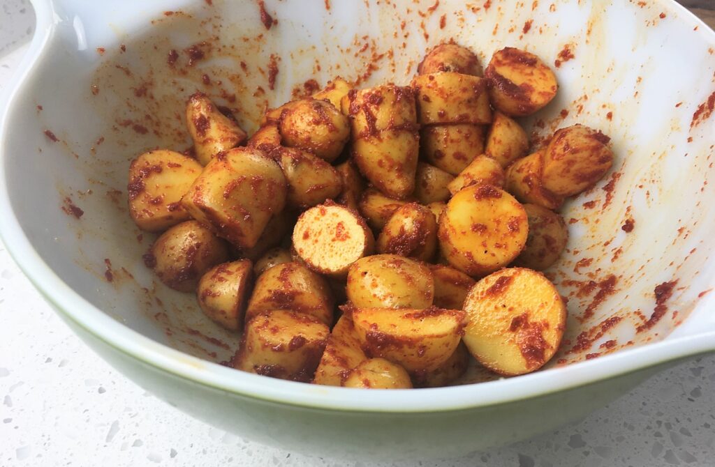 Spanish paprika mixed with chopped potatoes in a white bowl