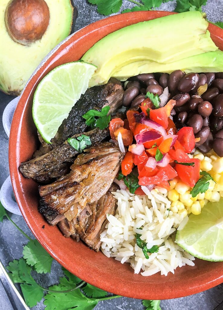 pork carnitas burrito bowls with lime wedge and avocado slices