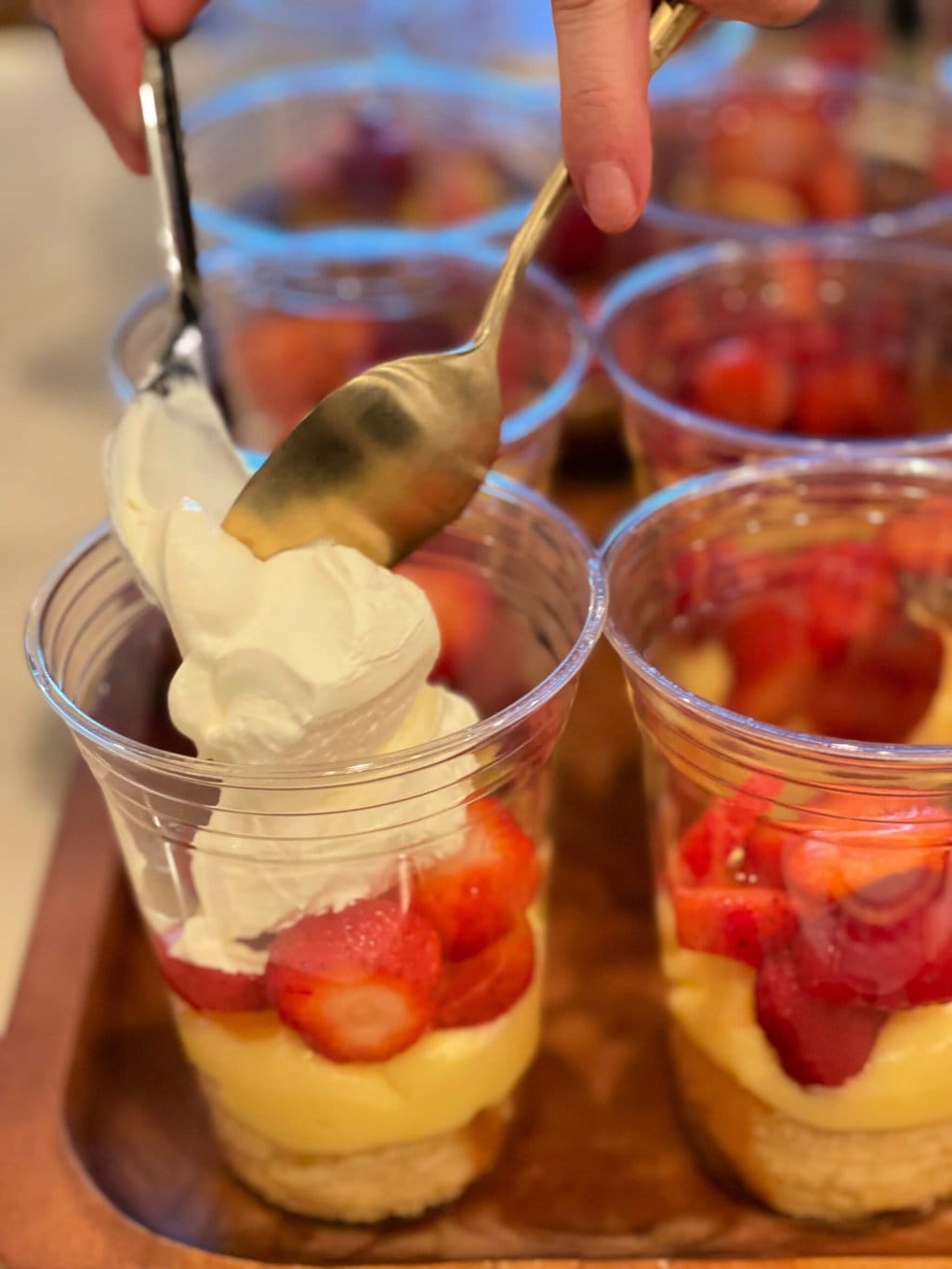 adding a layer of whipped cream to Individual Trifle Desserts with Pound Cake with berries and pudding