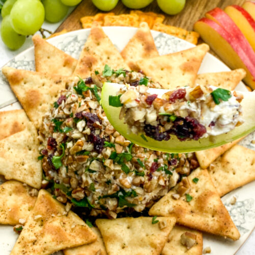 an apple dipped into orange cranberry cheese ball