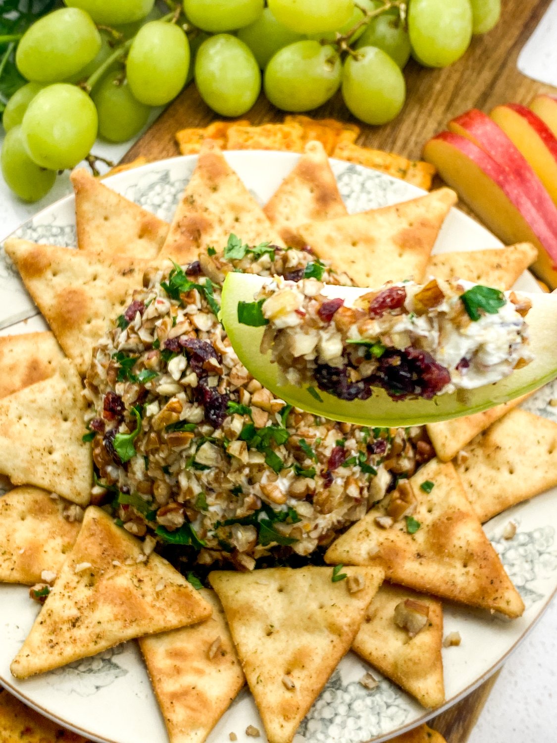 an apple dipped into orange cranberry cheese ball