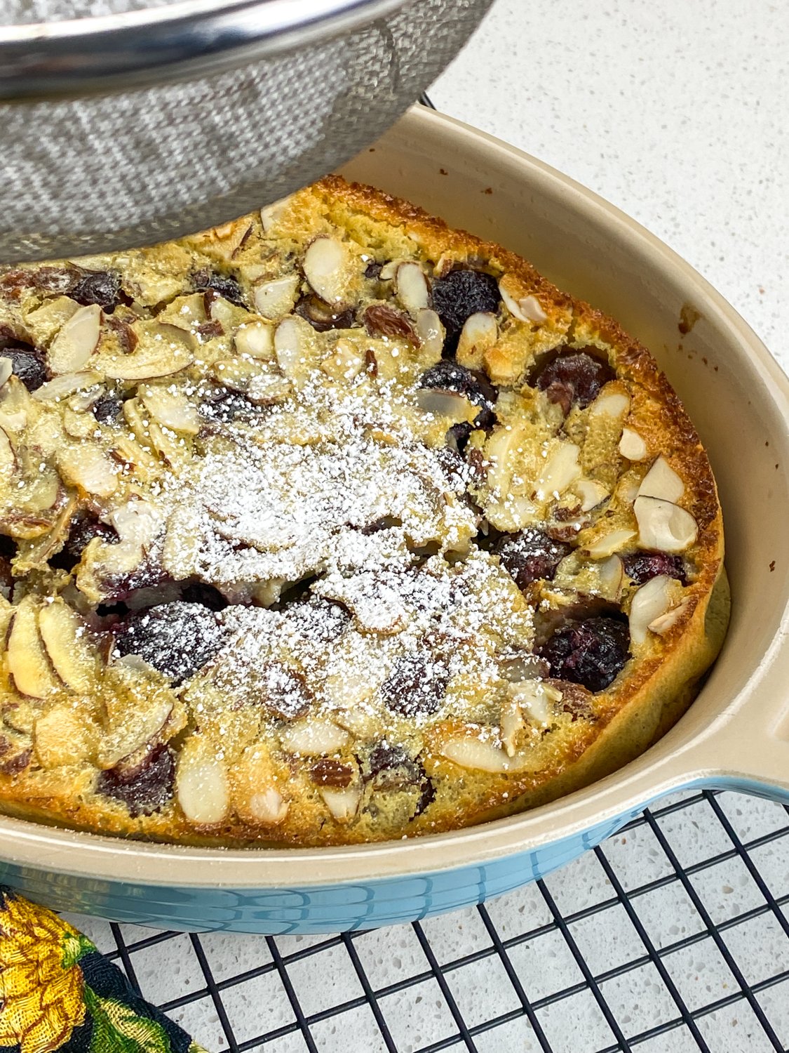 dusting cherry clafoutis with powdered sugar