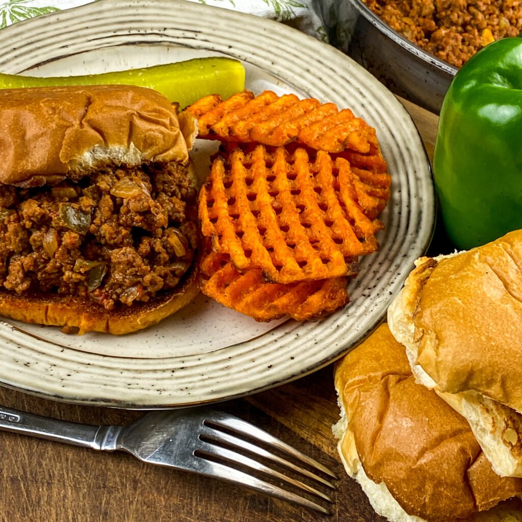 Homemade Sloppy Joes recipe photo in a bun served with potato wedges