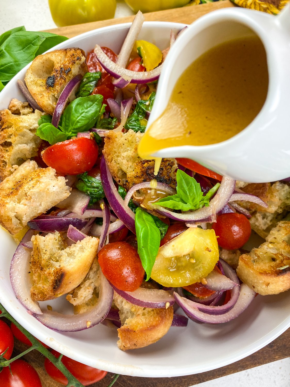 Panzanella Salad being drizzled with the vinaigrette