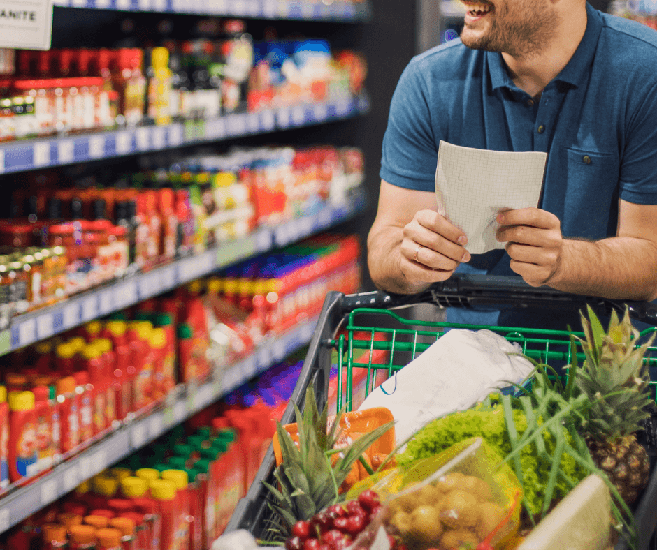 A man holding his grocery list while pushing his cart