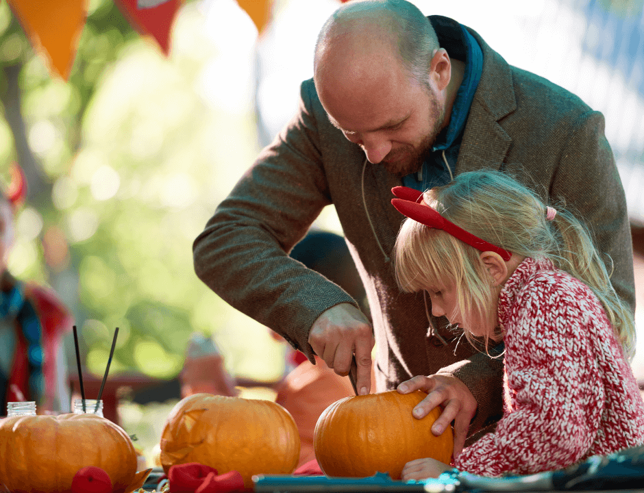 A father and daughter carving little pumpkins