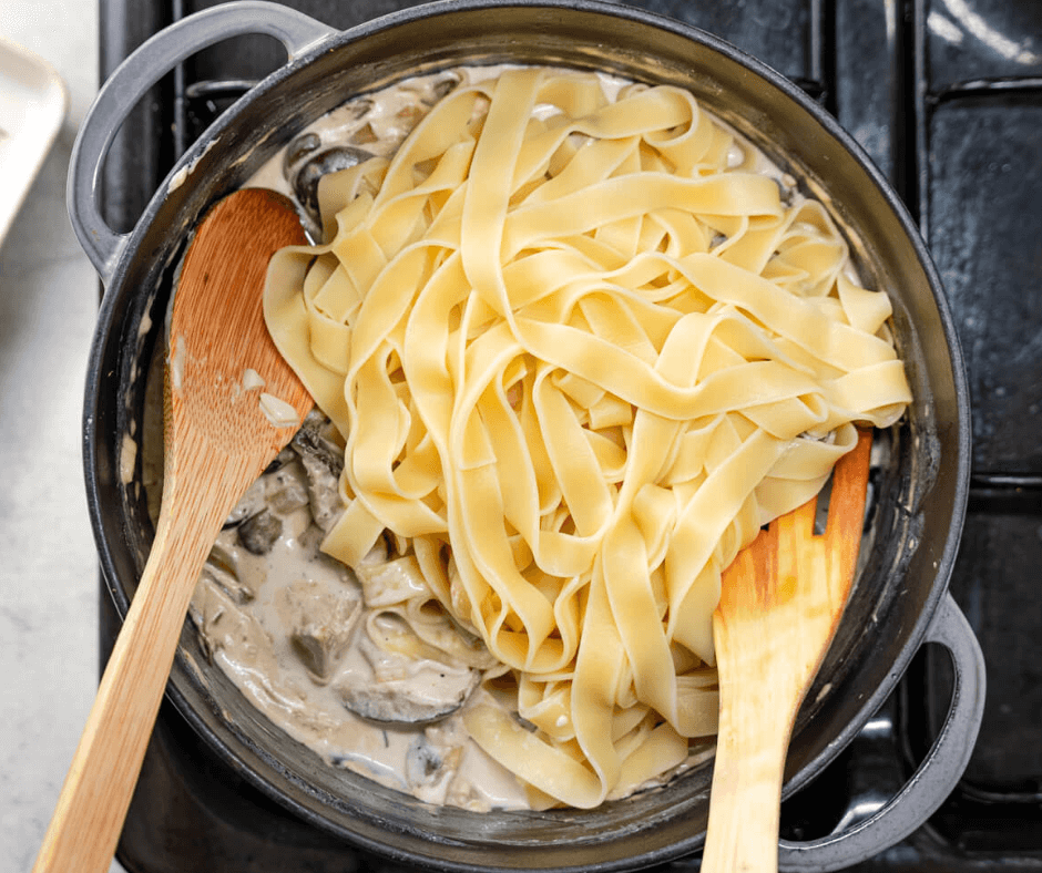 Adding the cooked pappardelle into the alfredo sauce