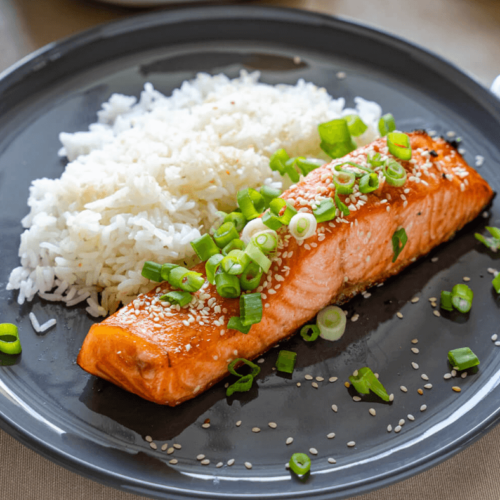 Honey Sriracha Salmon with cooked white rice on a gray plate