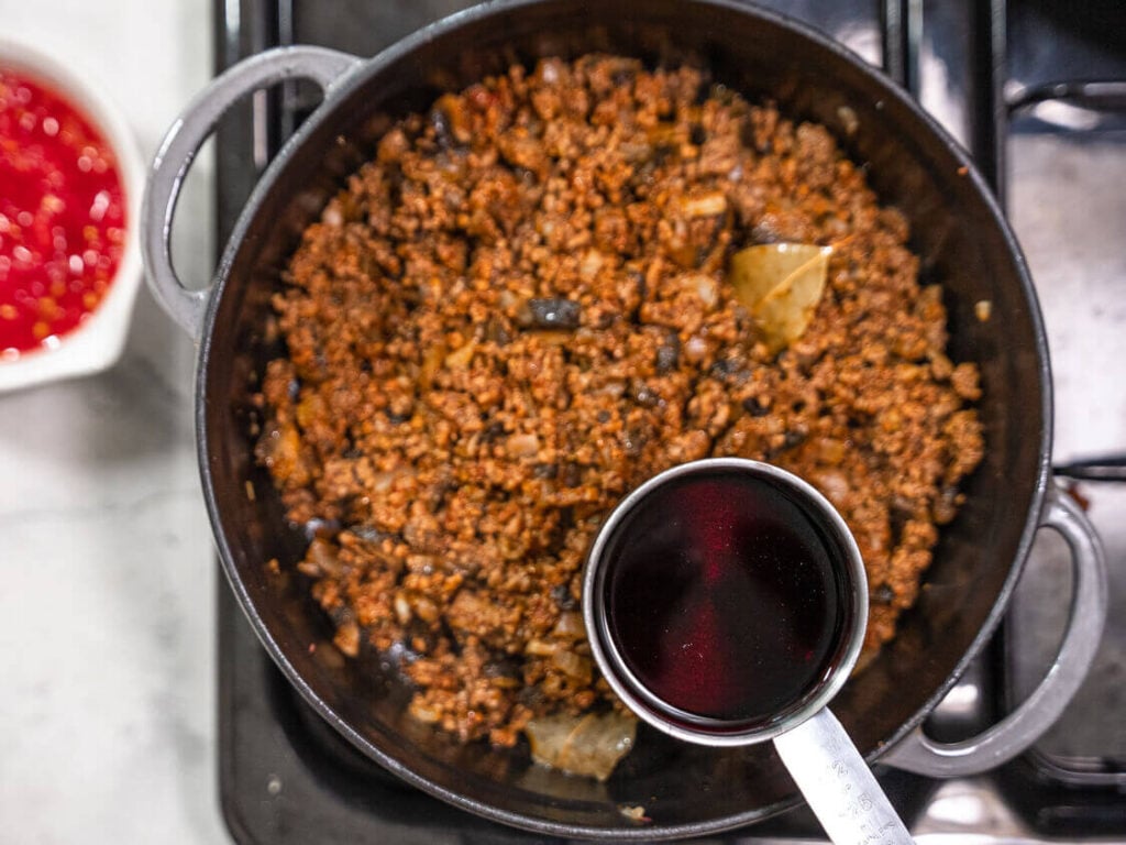 Pouring wine into the Bolognese sauce