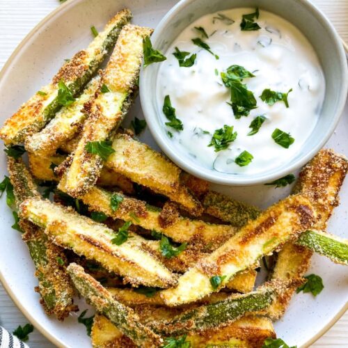 A closeup of Baked Zucchini Fries with Greek Yogurt Dip on a white plate