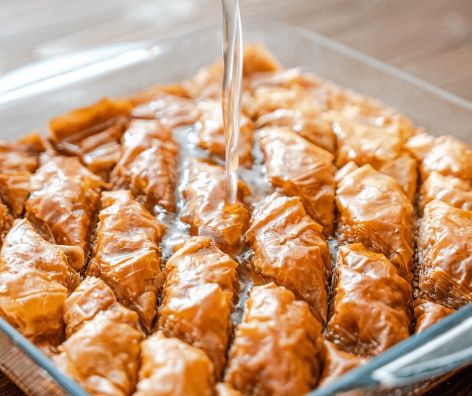 Adding the hot honey syrup on the baklava