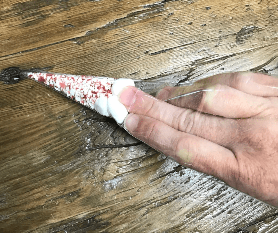 Adding the small marshmallows to the crushed peppermint into the clear cellophane