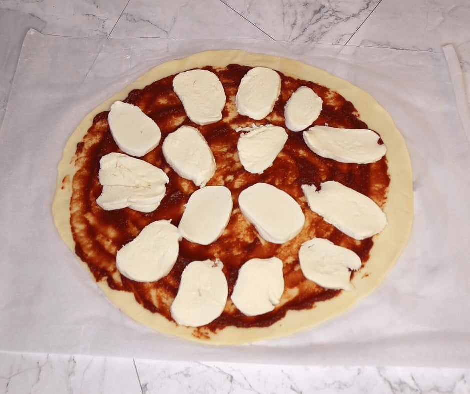 Mozarella cheese on a pizza dough and tomato sauce