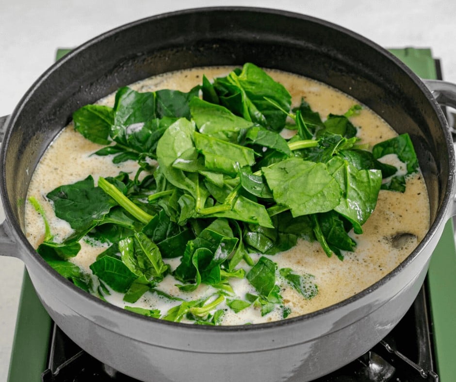 Placing the spinach on winter soup mixture