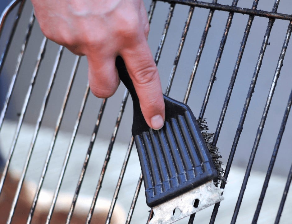 A person brushing and cleaning the grill