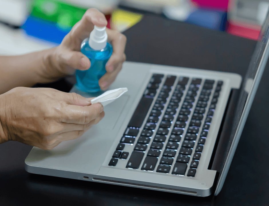 A person using vinegar to clean their laptop screen - Genius and Cheap Ways to Use Vinegar Around the House