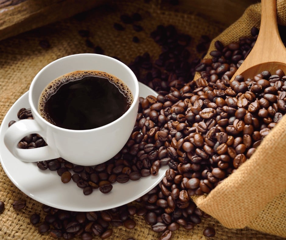 Coffee in a cup beside coffee beans