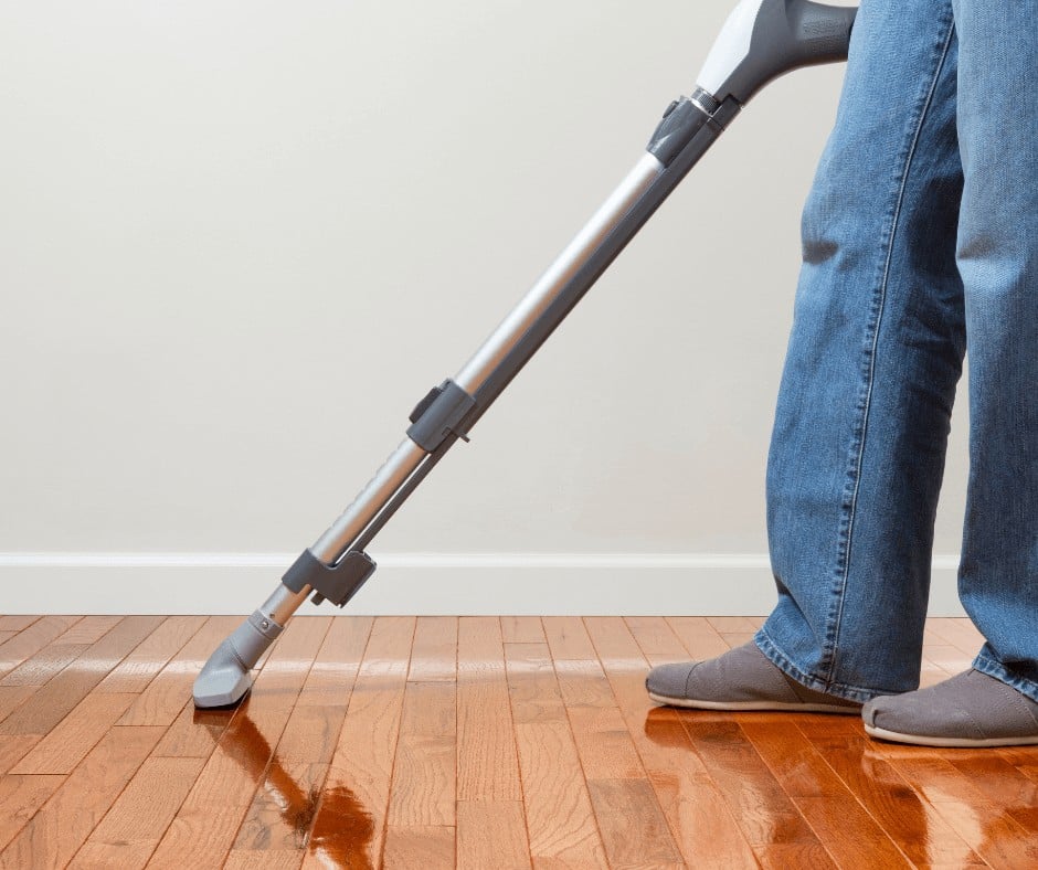 Man using a vacuum to clean hardwood floor
