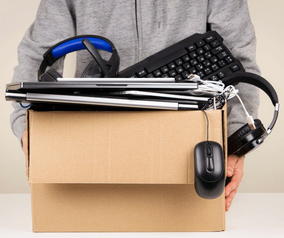 A man carrying a box of old electronics he's going to donate