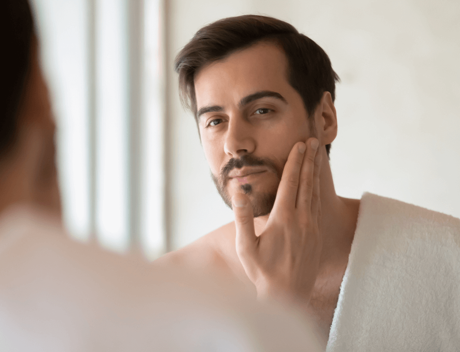 A man touching his face while looking at a mirror