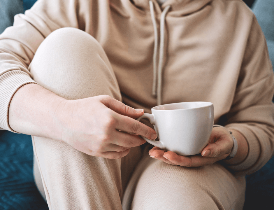 A person drinking something out of their white mug