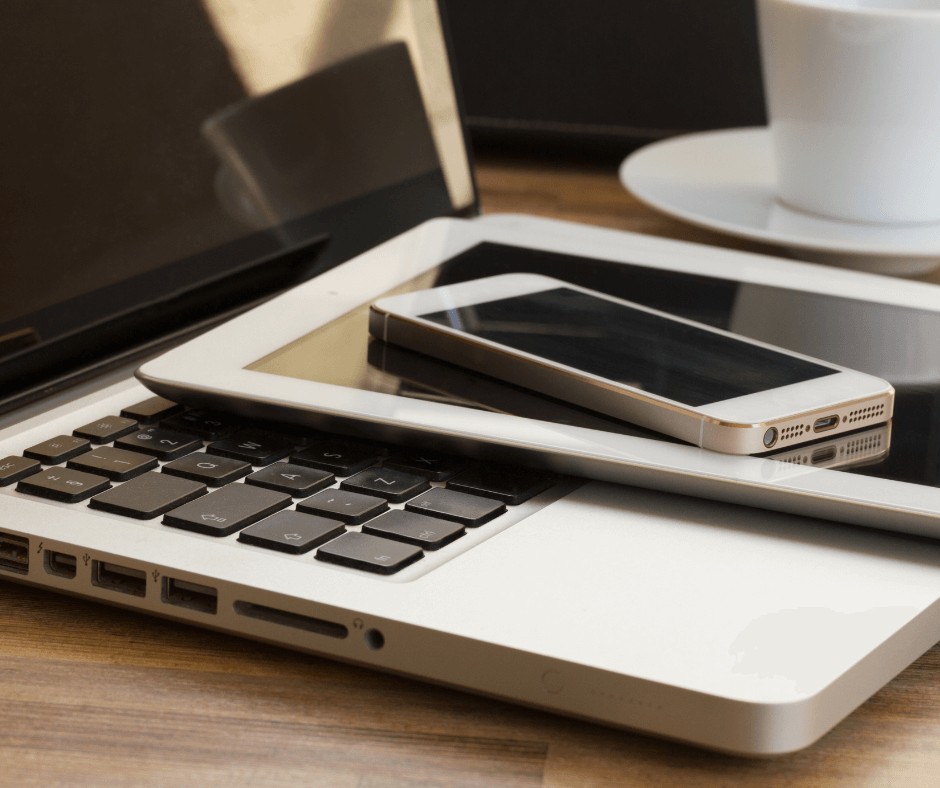 A phone and tablet laid on top of a laptop