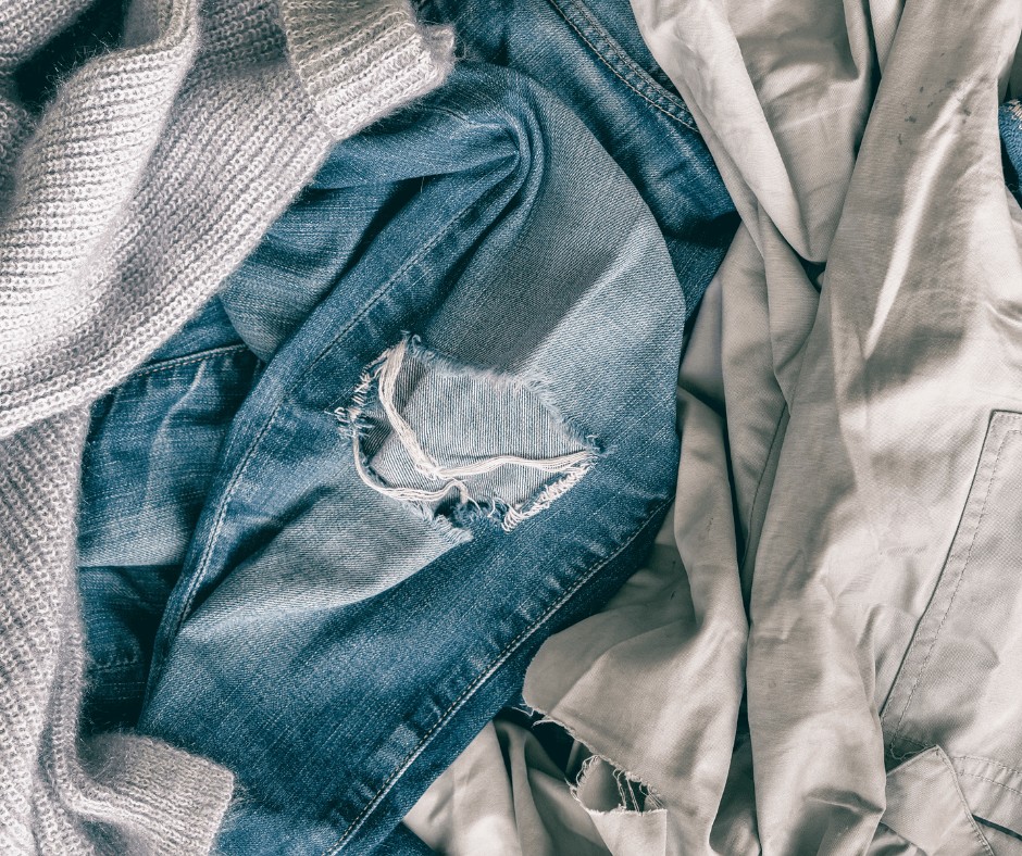 old clothes laid flat on the floor , jeans with a hole - Recycle Your Old Clothes
