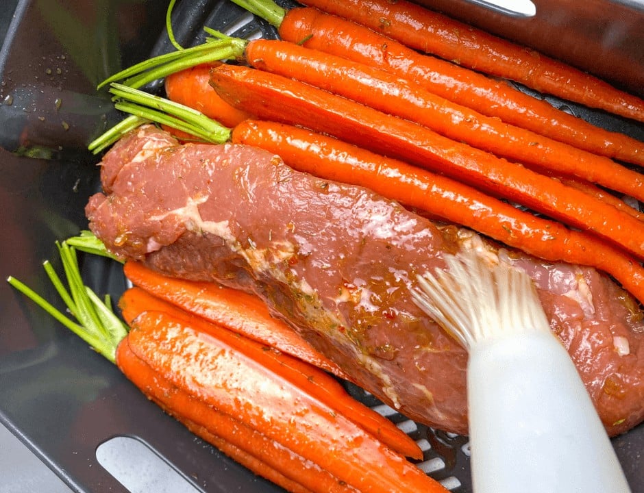 Adding the orange glaze to the carrots and pork tenderloin