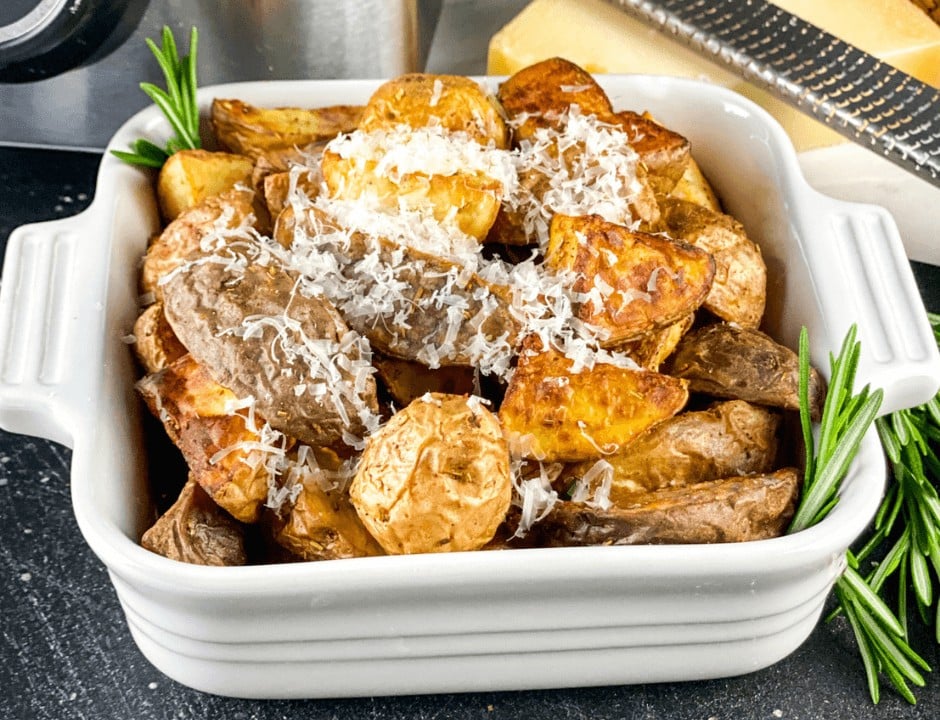 Golden brown Rosemary Garlic Potatoes with grated Parmesan cheese on top and rosemary garnish