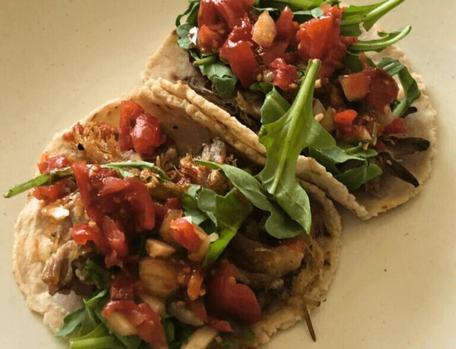 Tender shredded pork carnitas served in soft tacos shells 