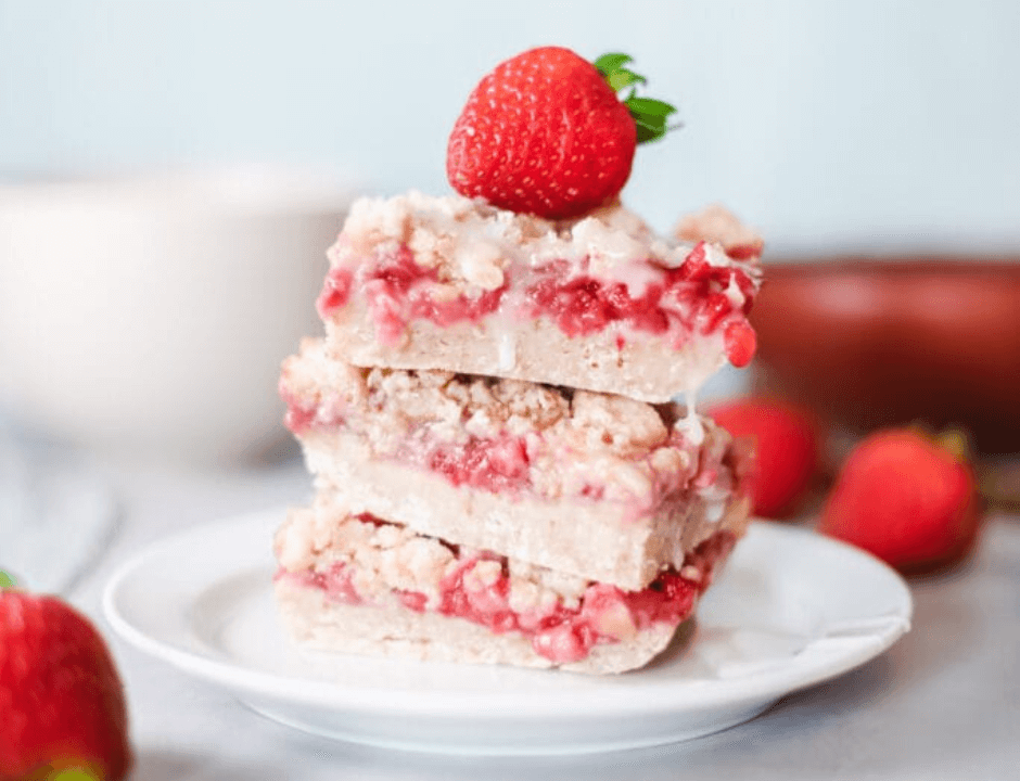 Three slices of Strawberry Banana Breakfast Bars served on a white plate and topped with a strawberry