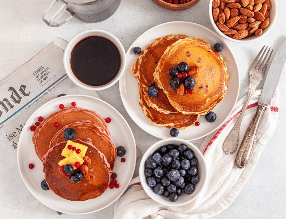 Two servings of Spiced and Fluffy Purple Blueberry Pancakes on a plate