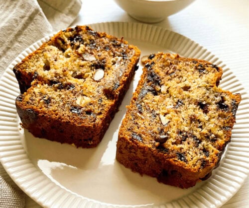 Two slices of Almond Chocolate Chip Banana Bread served on a white plate