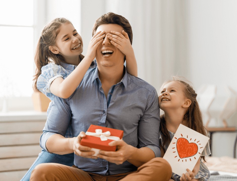 Two girls suprising their dad with a gift