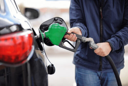 A person refueling his car at a gas station - Tips to Save Money on Gas