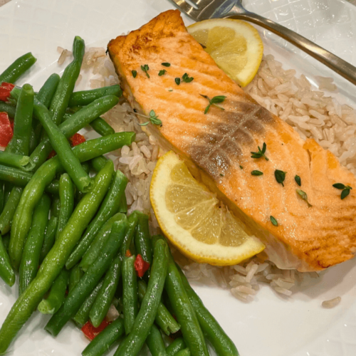 A plate of Lemon Butter Garlic Salmon with baked or lightly roasted green beans on the side