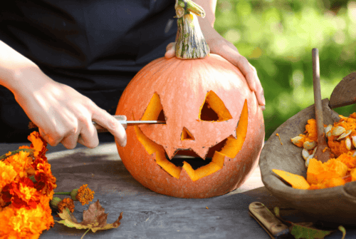 A woman carving a Halloween pumpkin