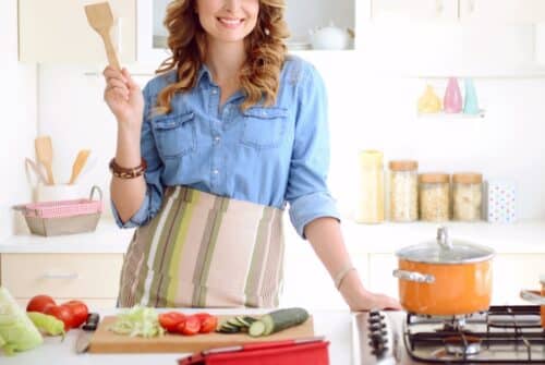 A woman holding a wooden spatula in the kitchen