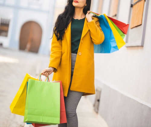 A woman holding multiple shopping bags - Designer Deals and Steals